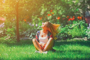 Happy free young woman sitting outdoors in yoga position with close up eyes on summer park grass Calm girl enjoy smile and relax in spring city air Mindset inner light peace concept. Bali asia sun joy