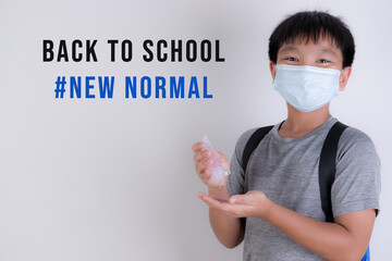 School boy wearing face mask and applying hand sanitizer, school reopen, back to school after covid-19 pandemic with text. New normal education concept.