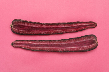 Halves of raw purple carrot on pink background, flat lay