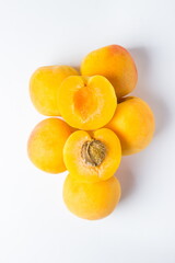 Apricots on a white background. On the apricots are two slices of apricot. One lobule with a bone, the other without.
