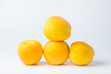Apricots on a white background. One apricot lies on top of the others.