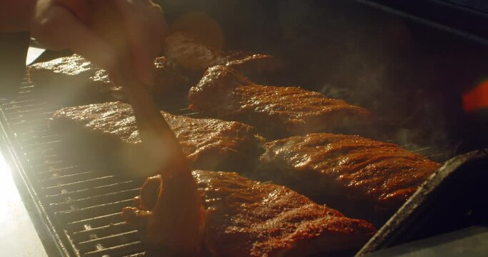 Juicy rack of ribs being basted and cooking on a bbq grill on a summer afternoon
