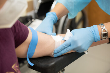 Nurse places a cotton ball and sanitary tape after taking a blood sample for Covid19 test.