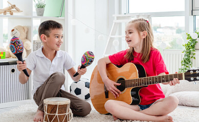 Smiling kids playing on drum and guitar