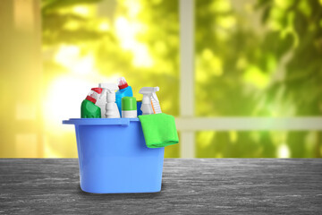 Bucket with cleaning supplies on grey stone surface indoors. Space for text