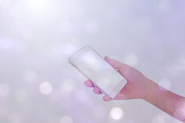 play smartphone in hand with white sunlight on bokeh background