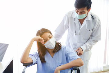 Obraz premium A patient woman wear face mask and sitting on wheelchair and covid-19 emergency treatment in a hospital room, doctors wear uniform protection