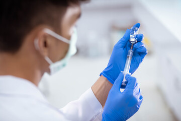 Doctor in blue glove filling syringe with vaccine