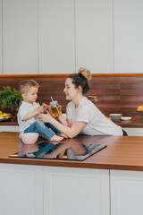 Fototapeta premium pregnant mother and son in the kitchen drink tea together 