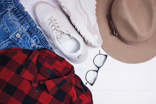 Flat lay composition with red chekered shirt, hat and sneakers.