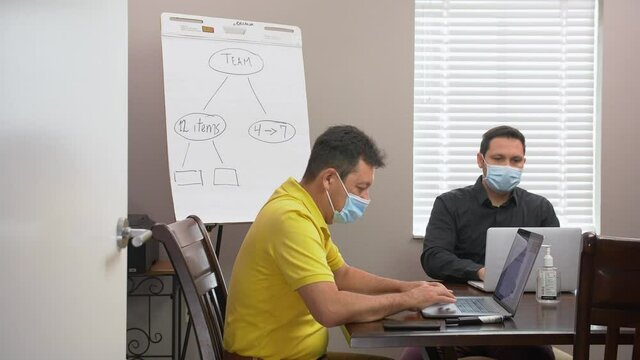 472 Two coworkers working during Covid19 pandemic with a mask