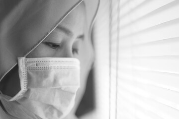 Sad woman in lockdown quarantine due to coronavirus covid 19 pandemic, looking trough window