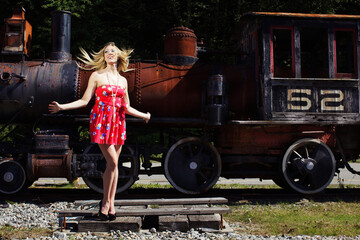 Beauty caucasian woman with long blonde hair posing near old train outside in sunny day