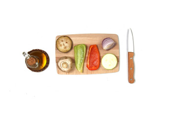 cut vegetables on cutting board, bottle of salad oil and a knife isolated on white background flat lay