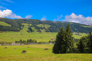 Fototapeta na wymiar Beautiful green alpine fields. Small villages high in the mountains.