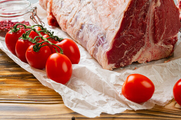 Raw T-bone steak with herbs on wooden board
