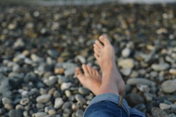 Crossed legs, with rolled jeans, stretched out on a pebble.