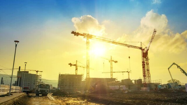 Time-lapse footage of a large construction site with several busy cranes in golden sunlight