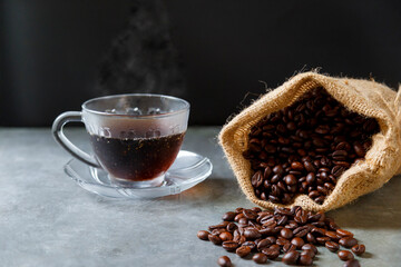Hot coffee in a cup and roasted coffee beans laid on the floor