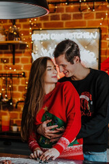 Young woman in red Christmas sweater and man making Christmas cookies at the kitchen.