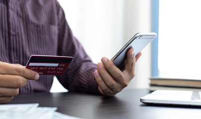 Young businessman with a credit card and a smartphone to prepare to pay online.