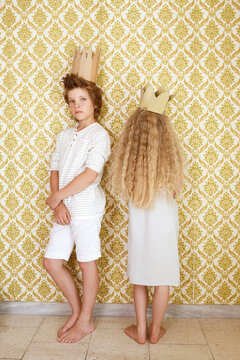 Boy and girl standing at a wall wearing cardboard crowns