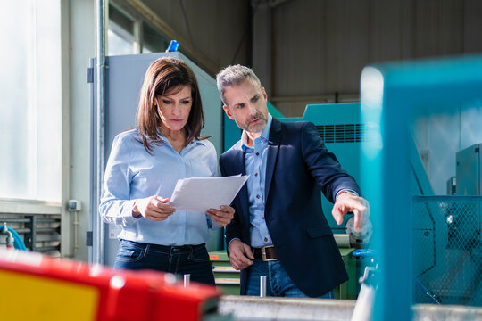 Businessman and businesswoman having a work meeting in a factory