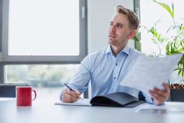 Businessman sitting at table in conference room holding papers