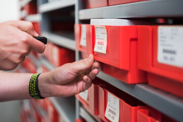 Close-up of man in storehouse of a factory using small scanner