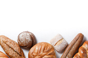Variety of loaves of bread and buns on white background