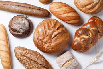 Variety of loaves of bread and buns on white background