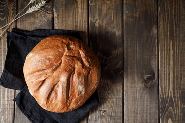 Homemade crusty loave of wheat bread on wooden background