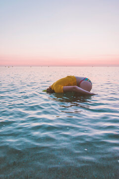 Side view of teenage girl enjoying in sea against sky during sunrise