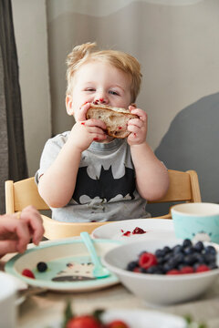 Portrait of smeared little boy eating bread with jam