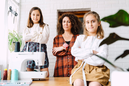 Portrait of mother and two daughters with sewing machine at home