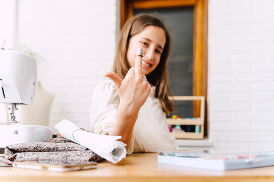 Mischievous girl at table with sewing machine giving the finger