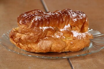 Eclair filled with pastry cream (custard) and topped with icing sugar