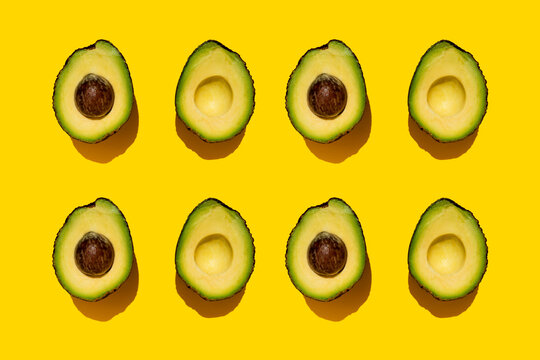 Pattern of halved avocados on yellow background