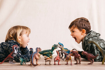 Brother and his little sister playing with toy dinosaurs
