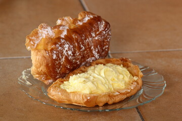 Eclair filled with pastry cream (custard) and topped with icing sugar