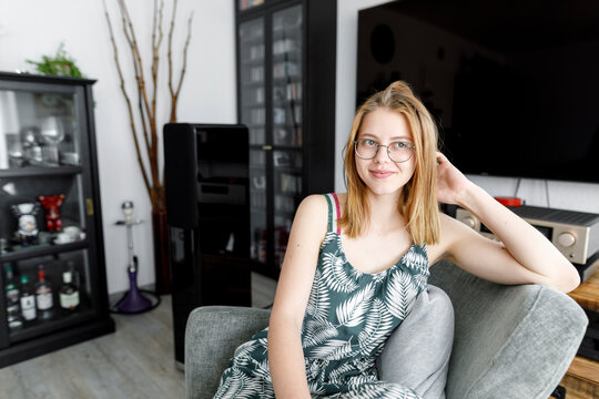 Portrait of smiling young woman sitting on armchair in the living room