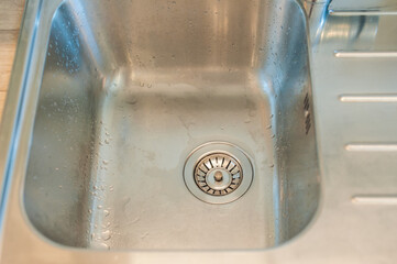 View of a clean sink, drain and running water. Kitchen sink, clean and tidy. Top view, close up