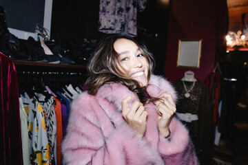 Portrait of smiling woman wearing pink fur jacket at thrift store