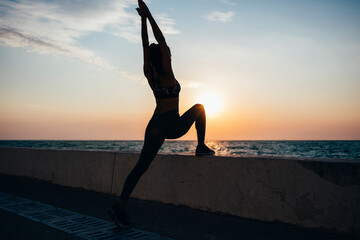 Silhouette woman practicing yoga at promenade during sunrise