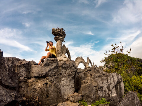 Vietnam, Ninh Binh Province, Ninh Binh, Male tourist taking photos in front of dragon sculpture