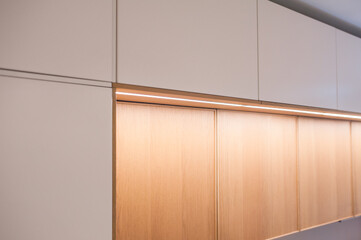 Fototapeta premium Kitchen cabinets, shelves with lighting, doors oak veneer and white. Close-up.