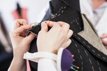 Close-up of seamstress pinning suit jacket