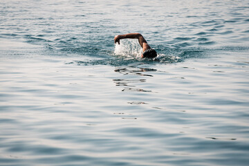 person swimming in water practicing open water swimming for triathlon