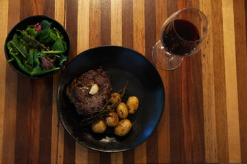 Dinner, Salad, Steak, Potatos and red wine on a wood table, meat and potatoes