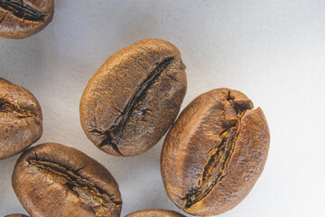 Brown coffee grains on a white paper background. Fragrant coffee grains close-up.
